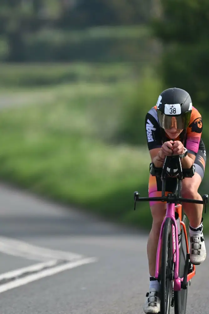 Madison S in a full aero tuck racing a time trial on her pink-wheeled TT bike
